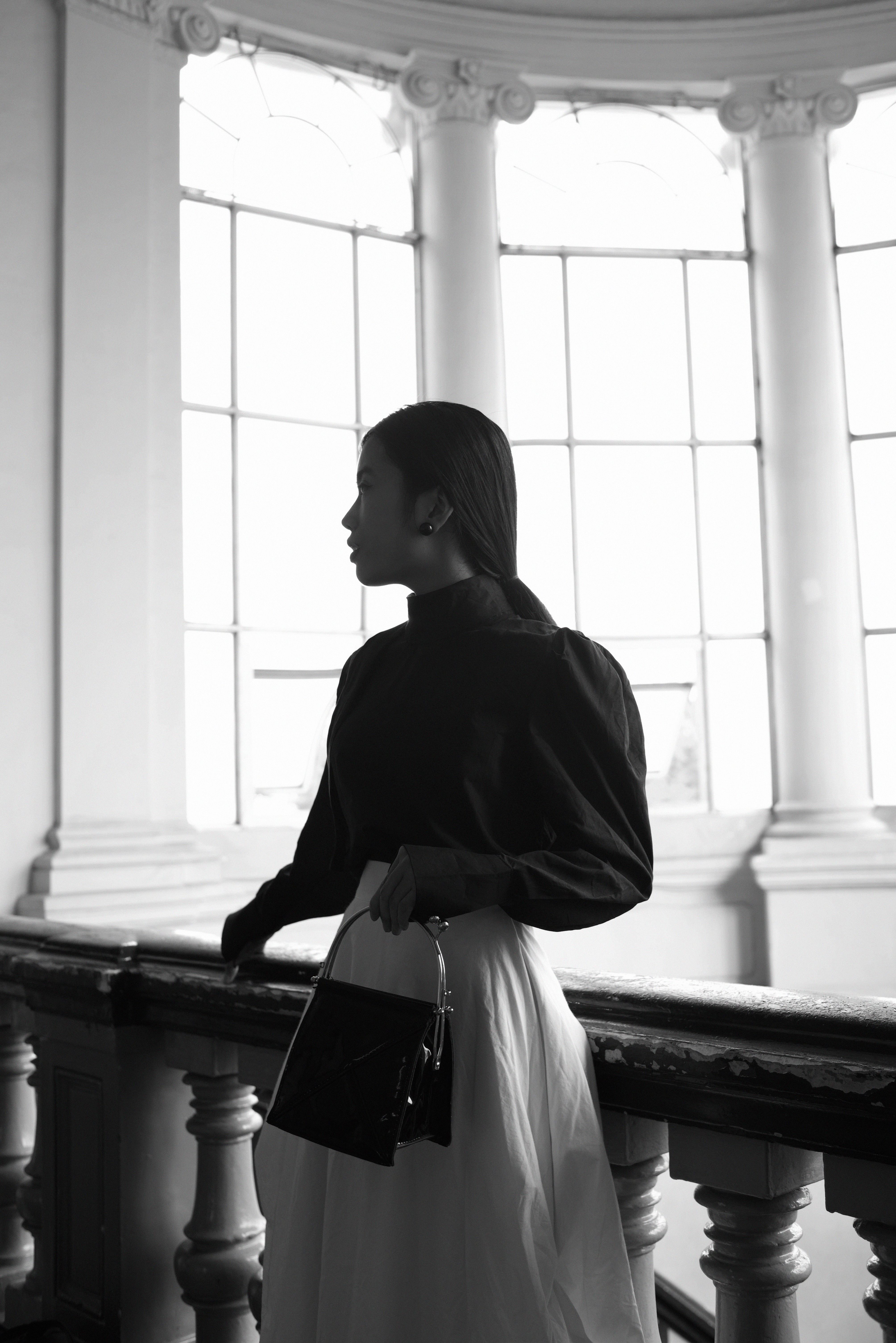 Black and white portrait of an elegant woman with handbag indoors, Ho Chi Minh City.