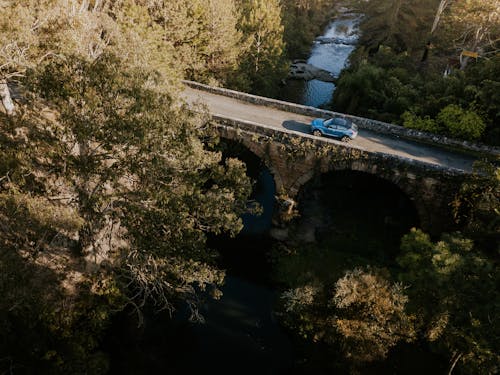 Blue Car on Bridge over River