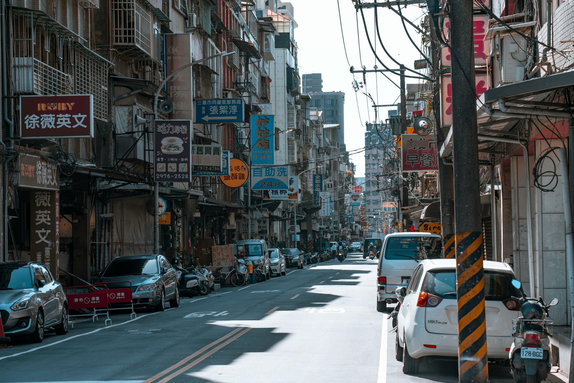 A busy street lined with cars and various colorful business signs on a sunny day.