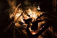 A vivid campfire with glowing flames and charred logs in the dark night atmosphere.