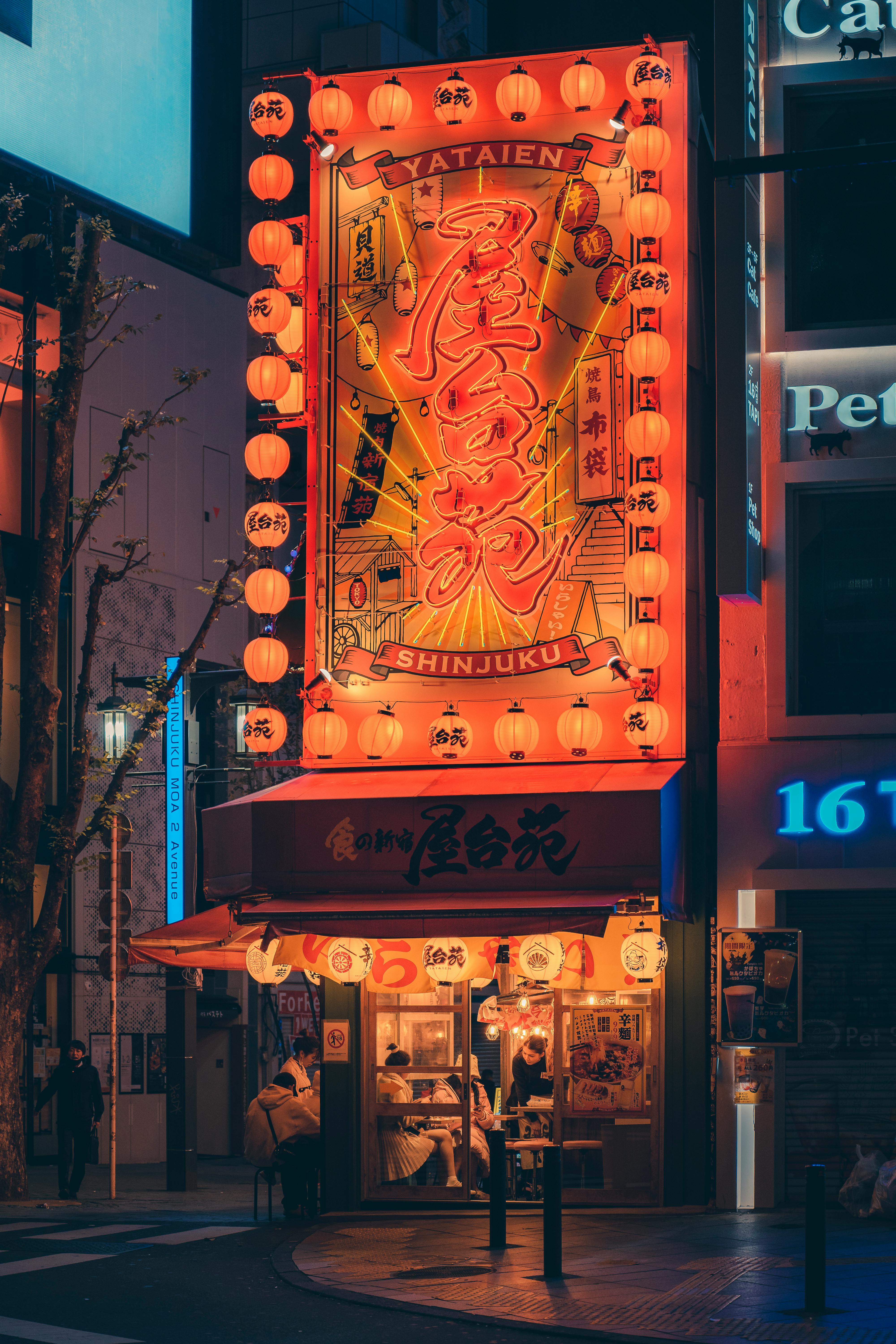 Neon-lit facade of a Shinjuku restaurant, featuring illuminated Japanese signage and lanterns.