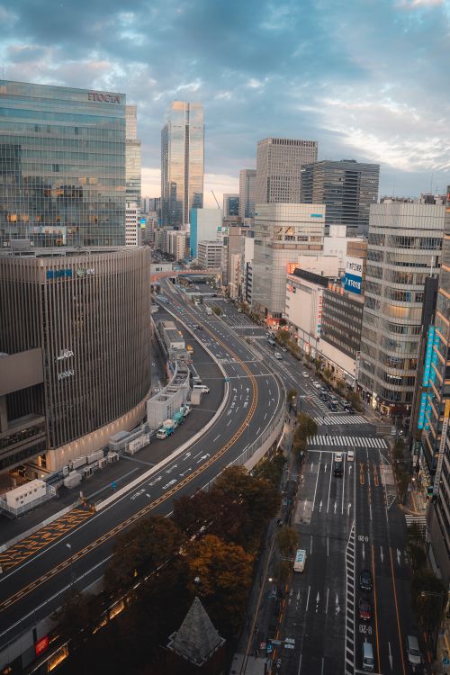 Free Aerial view of bustling city with skyscrapers and a winding highway under a cloudy sky. Stock Photo