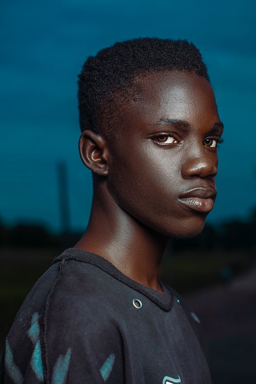 Free Portrait of a young man wearing a black t-shirt against a twilight backdrop in Minna, Nigeria. Stock Photo