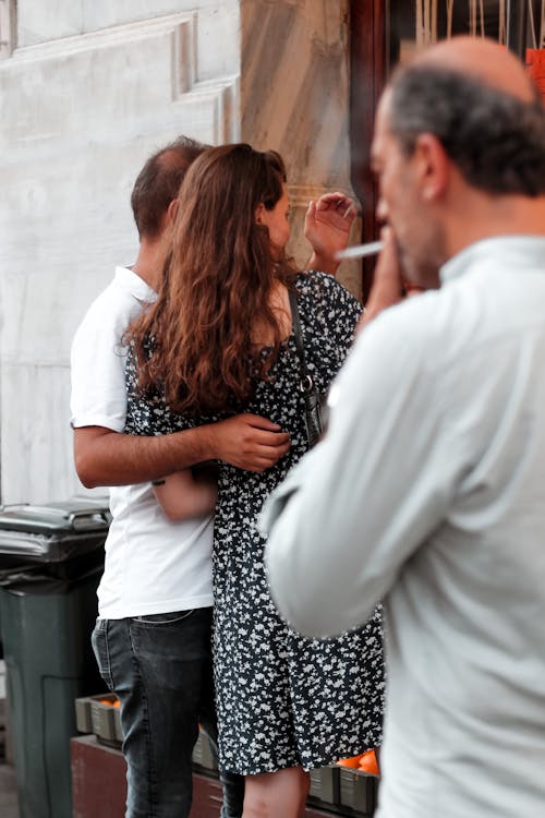 Smoking Man and Couple Hugging behind