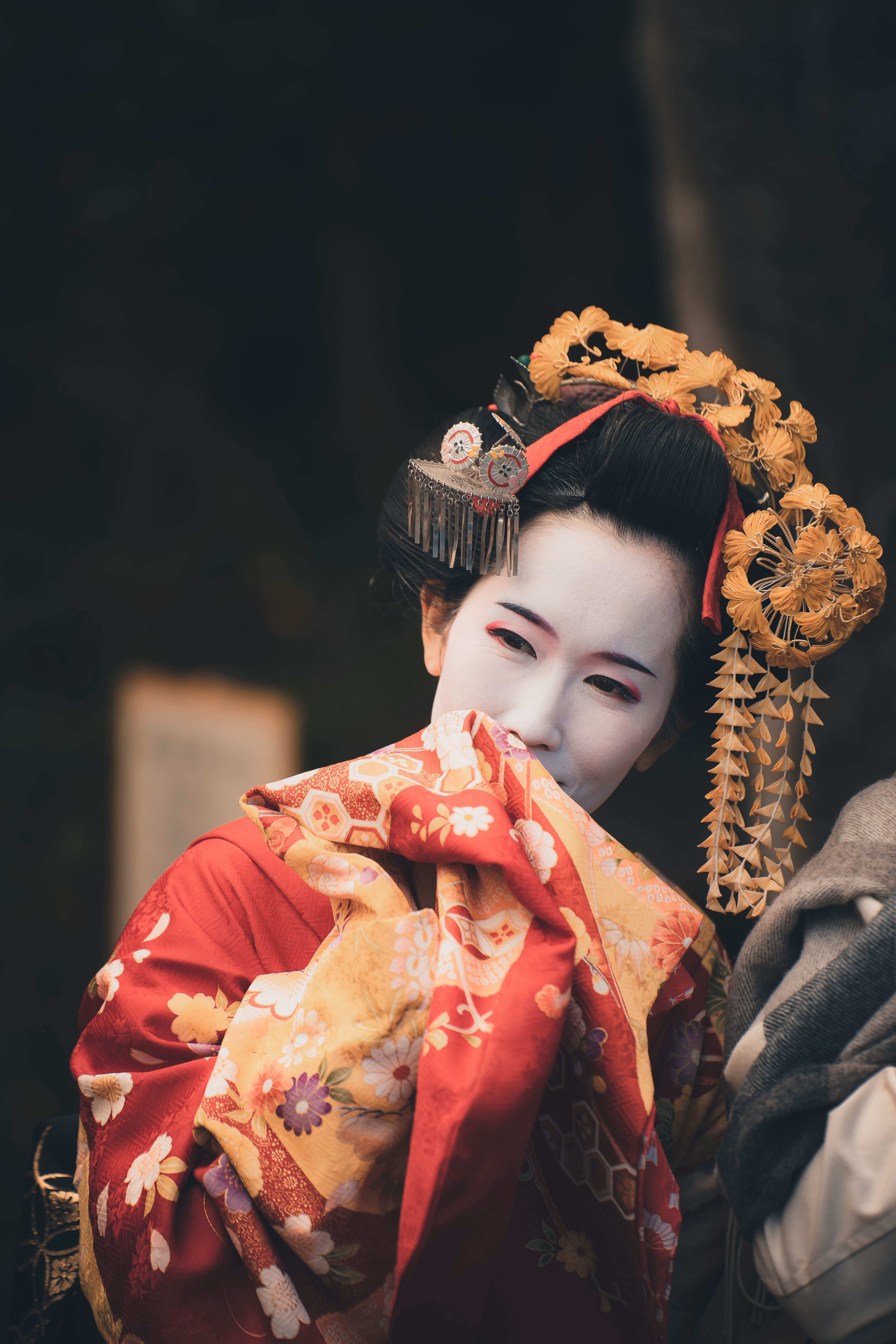 Portrait of a geisha in vibrant traditional clothing, capturing a candid moment.