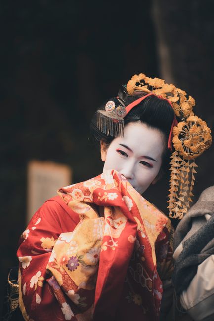Portrait of a geisha in vibrant traditional clothing, capturing a candid moment.