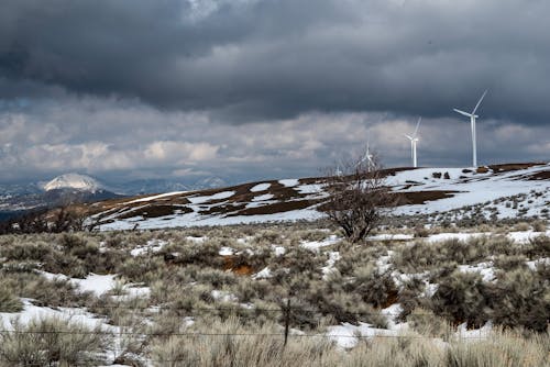 View of Wind Turbines Standing on Top of Snowcapped Hills 