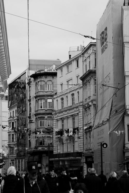 Free Black and white photo of a bustling urban street featuring historic buildings and passing pedestrians. Stock Photo