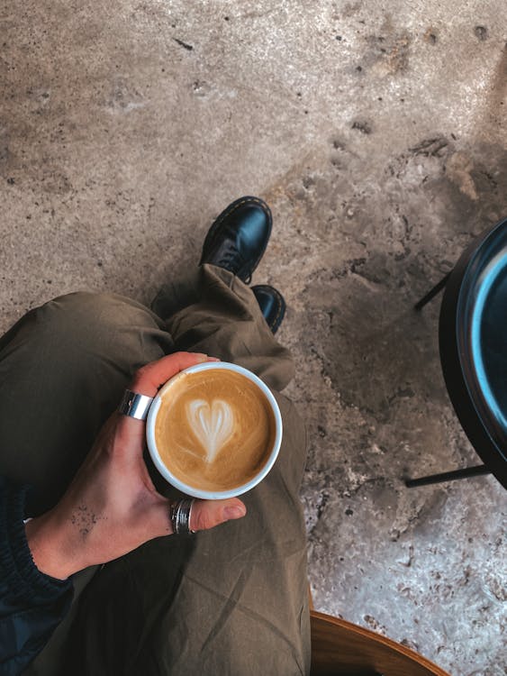 Man Sitting and Holding a Cup of Coffee with Latte Art 