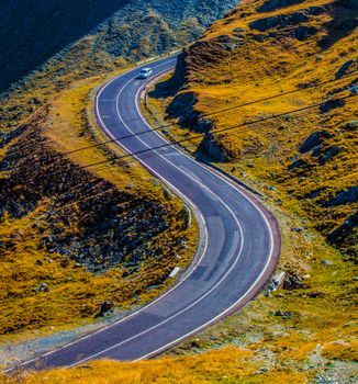Aerial view of a winding road cutting through a picturesque mountainous landscape during daytime.