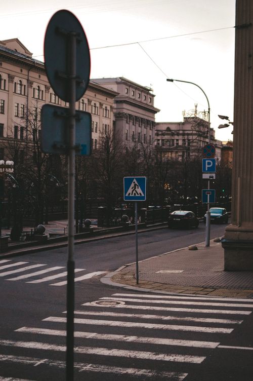 Free A tranquil urban street view featuring crosswalks, road signs, and historical architecture at dusk. Stock Photo