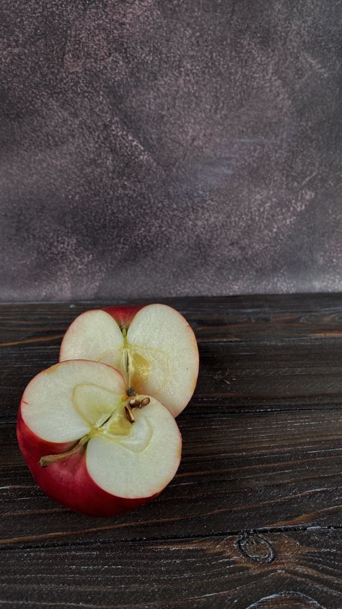 Free Sliced red apple halves laid on a rustic wooden table with a textured backdrop. Perfect for healthy eating themes. Stock Photo
