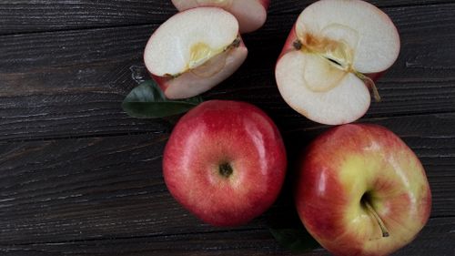 Free Fresh red apples with cut halves on a dark wooden background, Kharkiv, Ukraine. Stock Photo