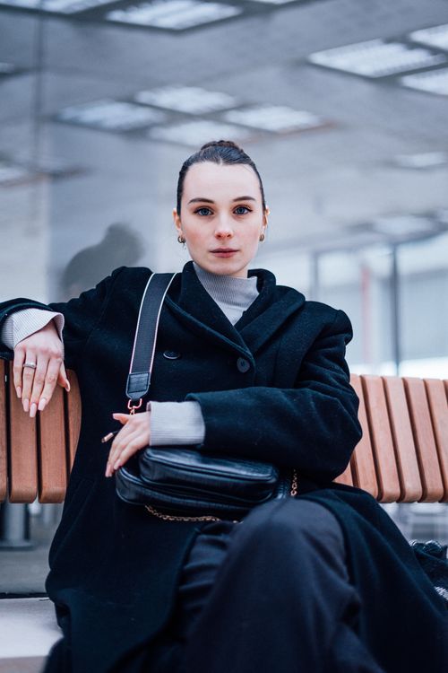 Free Elegant woman sitting on bench in urban area, showcasing modern fashion style. Stock Photo