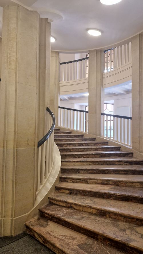 Free Vertical shot of a luxurious indoor curved marble staircase with elegant design details. Stock Photo