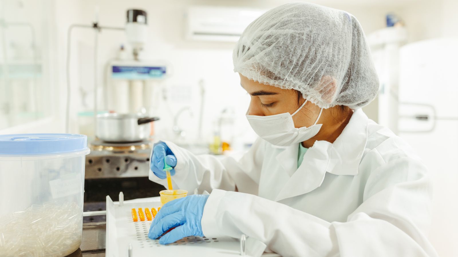 A scientist wearing protective gear performs a meticulous experiment in a laboratory setting.