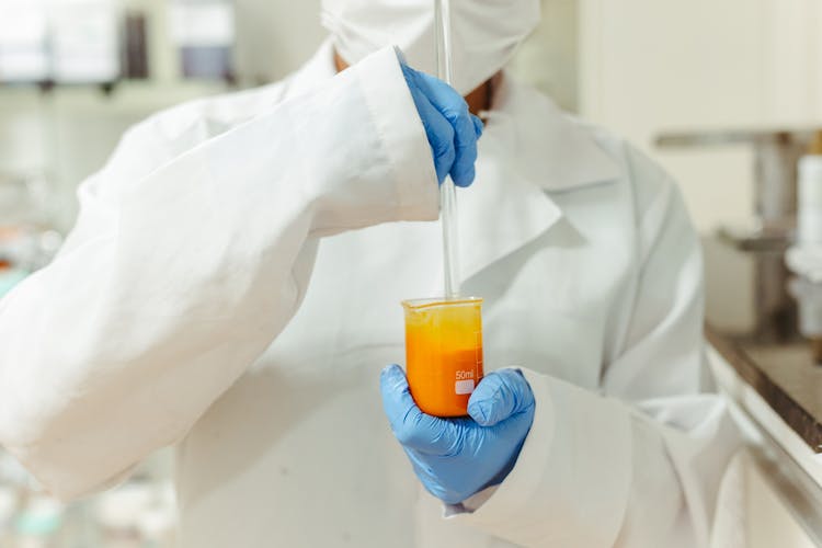 Scientist In Laboratory Coat Holding A Test Tube And A Flask 