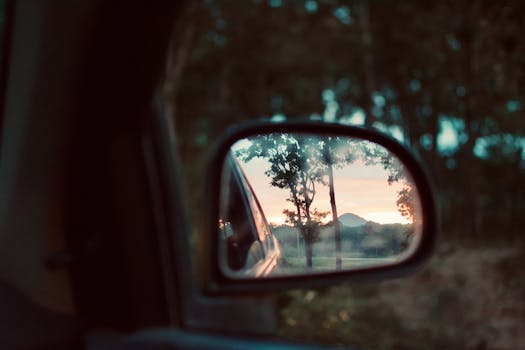 Reflection of a scenic sunset and mountain landscape through a car mirror. Vibrant and peaceful view.