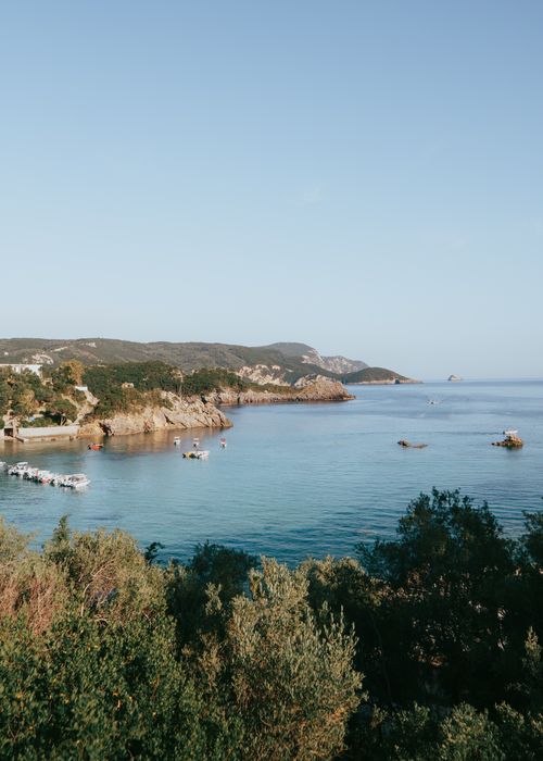 Free A picturesque seascape of Kerkyra, Greece with boats and a rocky coastline under a clear sky. Stock Photo
