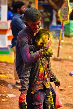 Two boys celebrate Holi joyfully in Odisha with vibrant colored powders during the spring festival.