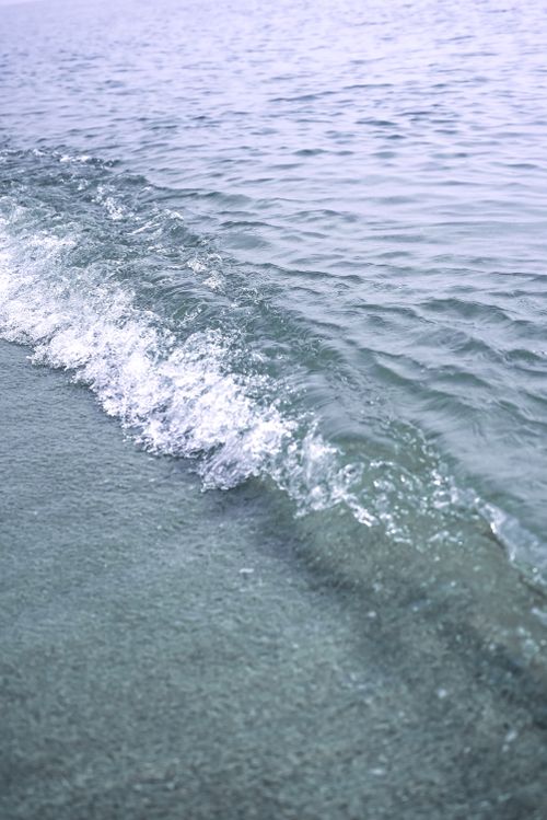Free A serene close-up of a gentle ocean wave lapping at a sandy shore, showcasing natural beauty. Stock Photo