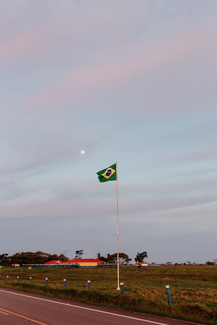 A Brazilian Flag On A Flagpole Near The Road 