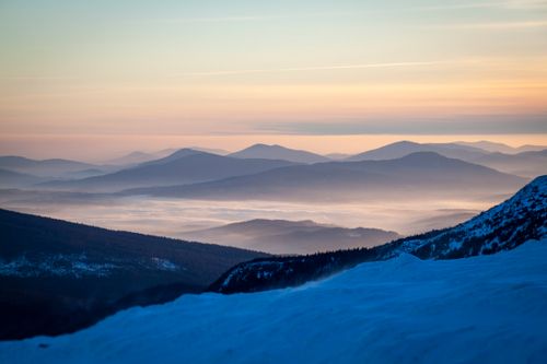 Free Enjoy a stunning sunrise over foggy mountain valleys with snow-capped peaks, creating a serene landscape. Stock Photo