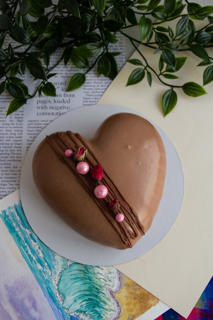 Still Life With A Watercolour Painting, Heart Shape Chocolate Cake, And A Houseplant