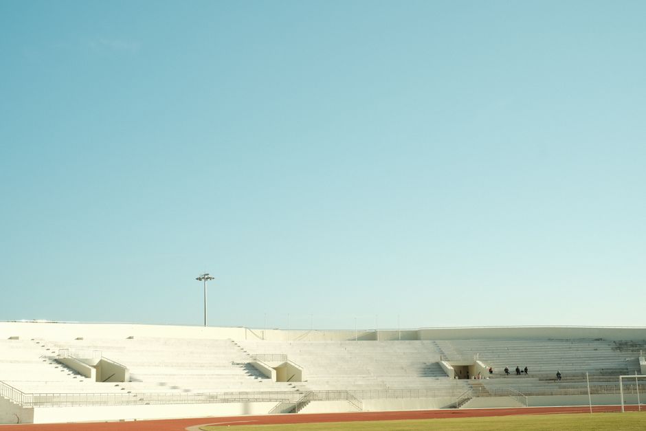 A serene image of empty stadium bleachers with a clear blue sky overhead.
