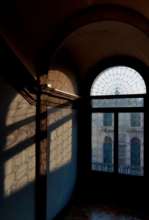 Free A Venetian window with intricate design casting beautiful shadows inside a historic building in Venice, Italy. Stock Photo