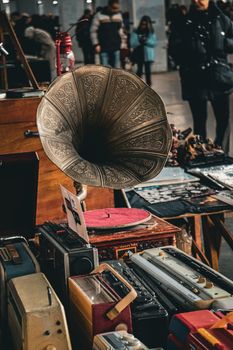 Explore a vintage gramophone and radios displayed at a bustling flea market.