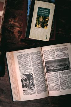 Open book on a wooden table, showcasing classic literature and images.