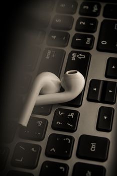 Close-up of wireless earbuds resting on a laptop keyboard, showcasing modern technology.