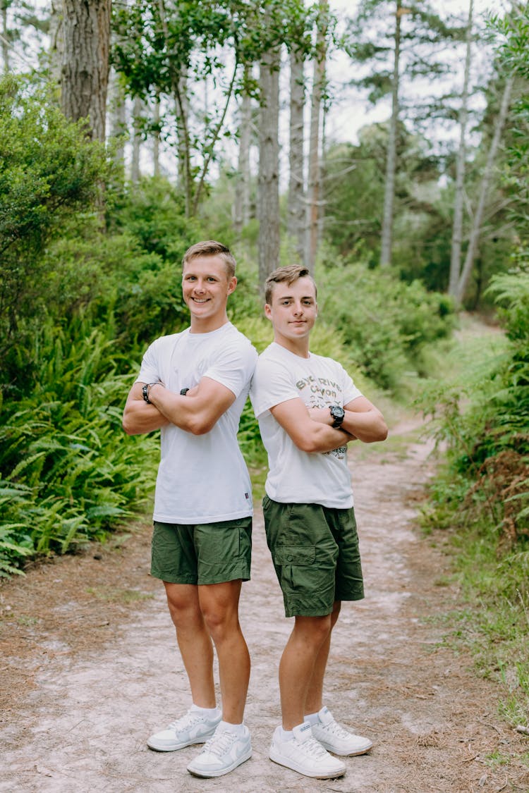 Two Boys Standing On A Footpath In A Forest 