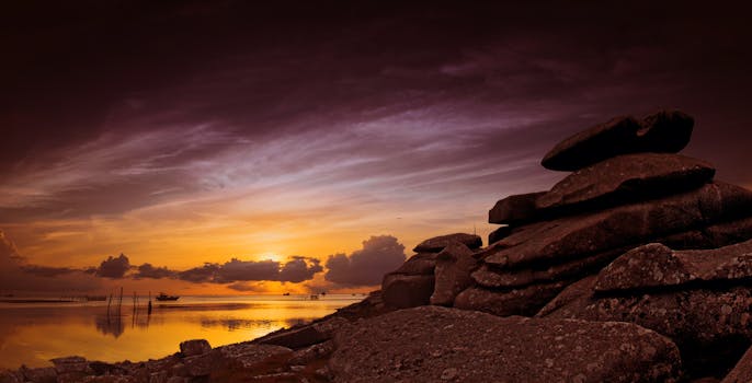 Serene ocean sunset with dramatic rocks and vibrant skies, perfect for nature and travel themes.