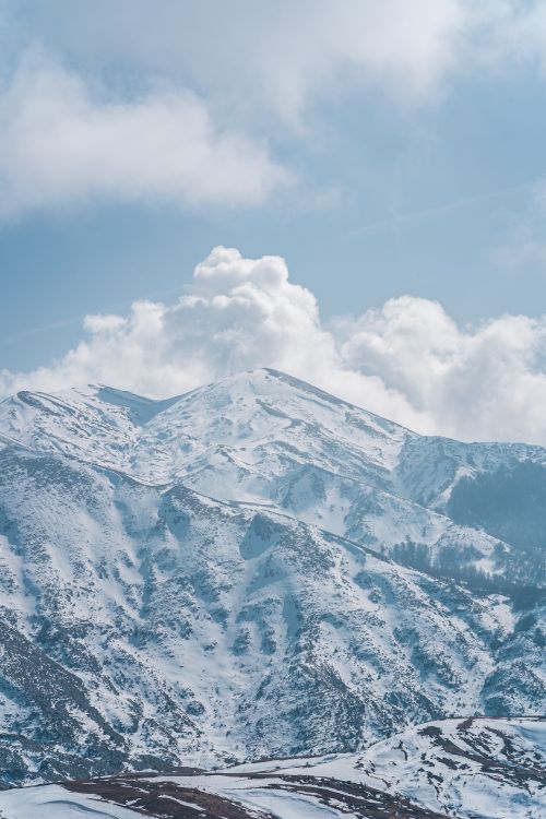 Free Scenic view of a snowcapped mountain range with blue sky and white clouds. Stock Photo