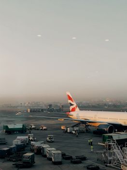 A commercial airplane parked on the tarmac at Mumbai Airport during dawn, with a clear view of the urban skyline.