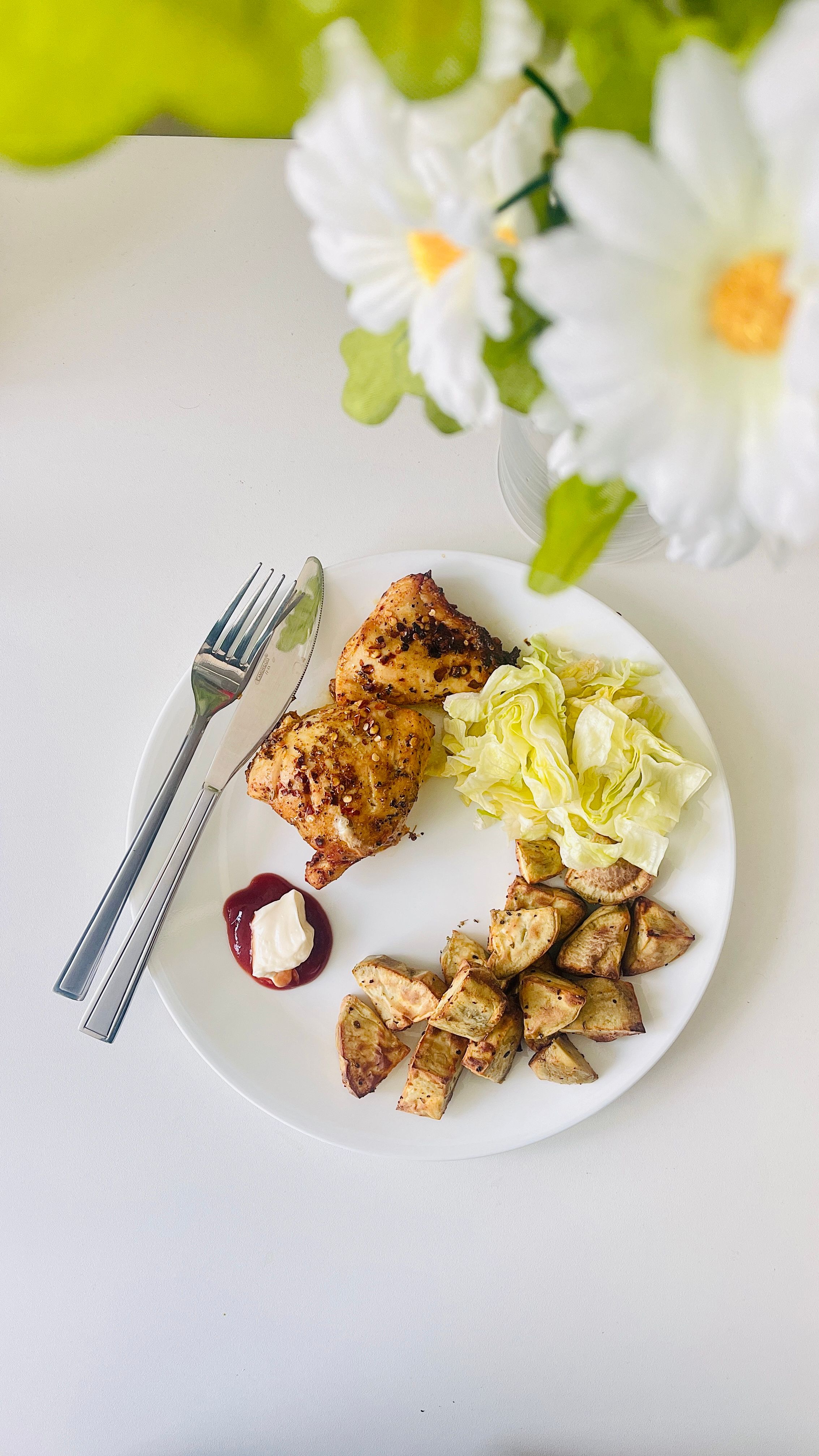 A delicious chicken and vegetable meal served with roasted potatoes and lettuce on a white plate.