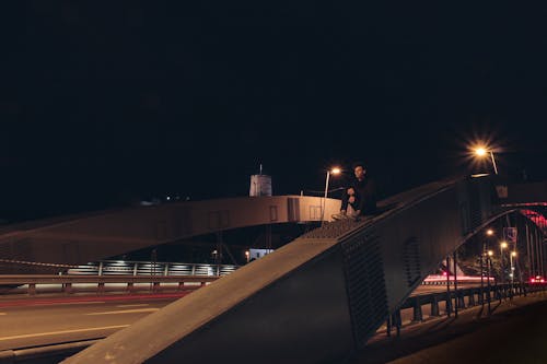 Man Zit Op Grijze Stalen Brug