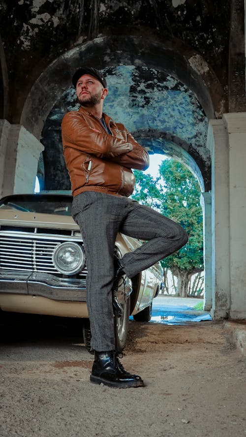 Man in a Brown Leather Jacket Leaning Against a Classic Car