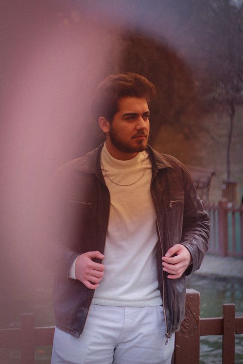 Free Man posing outdoors wearing a leather jacket and sweater, showcasing fashion style. Stock Photo