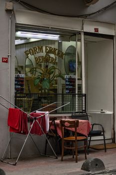 Quaint Istanbul street scene featuring a traditional barber shop with outdoor seating and drying towels.