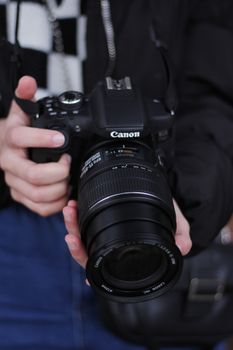 Close-up of a person holding a DSLR camera, focusing on the lens and grip.