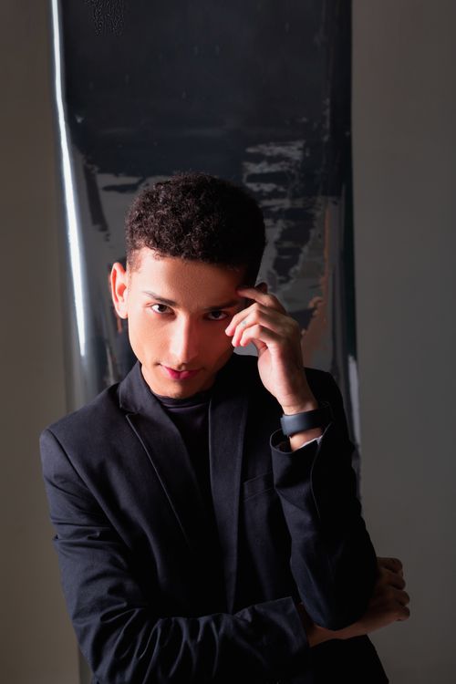 Free A young man confidently posing in a modern black suit, exuding elegance and style. Stock Photo