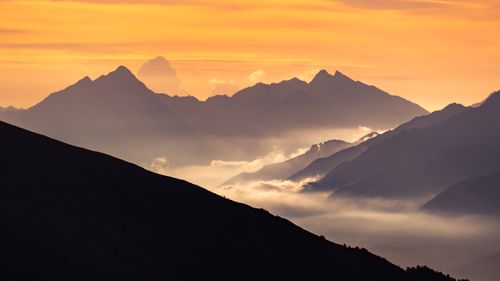Free Stunning sunrise over misty mountains in the Aosta Valley, Italy, capturing serene nature and vibrant colors. Stock Photo