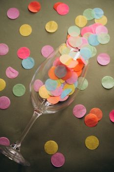 A vibrant display of colorful confetti spilling from a wineglass, evoking a festive party atmosphere.