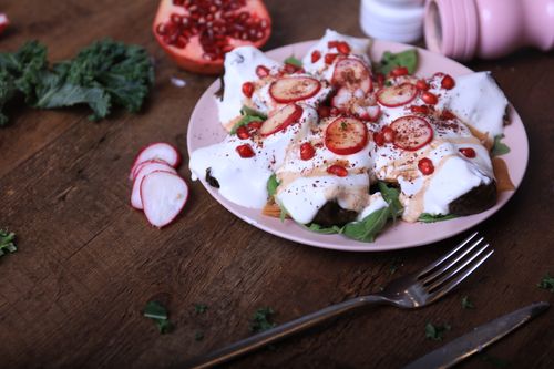 Free Colorful Middle Eastern dish featuring creamy yogurt, radishes, and pomegranate on a rustic dining table. Stock Photo
