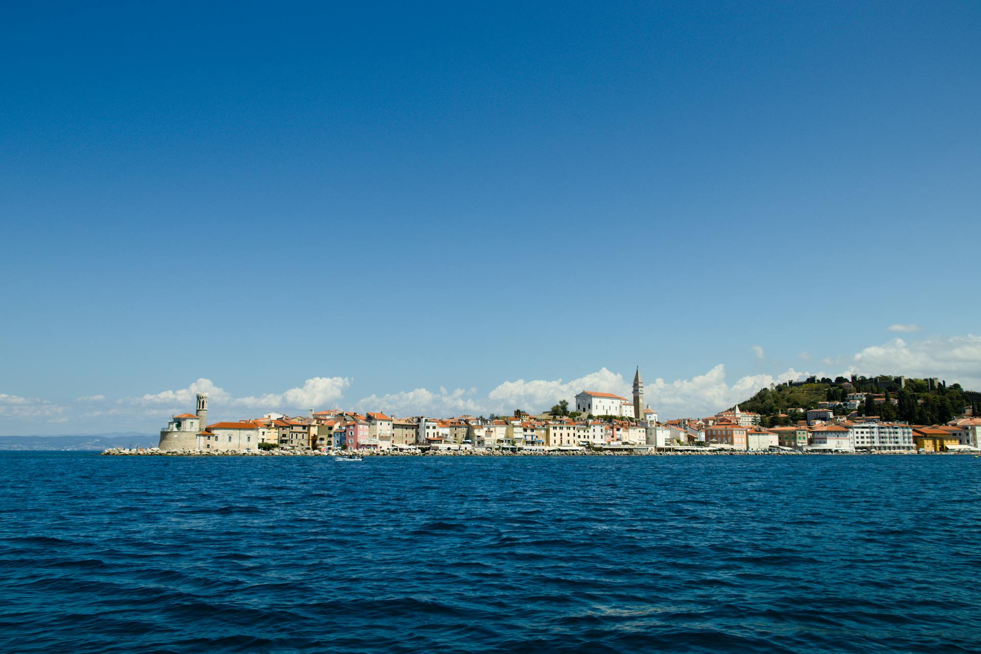 Scenic view of Piran, Slovenia from the sea, showcasing its historic architecture under a clear blue sky.