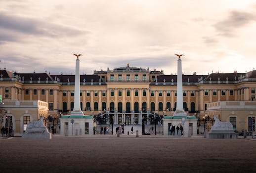 Majestic Schonbrunn Palace with people in Vienna during sunset.