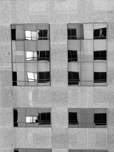 Black and white facade of a modern building in Brasília showcasing reflective windows.